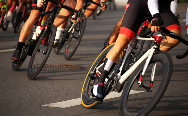 A close-up shot of professional cyclists riding high-performance road bikes during a competitive race. Capturing speed, precision, and aerodynamics in cycling. - Post and Saddle Bike Co.